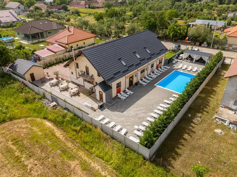 Vedere aeriană a pensiunii, cu acoperiș, piscină și câmpuri de cereale în fundal