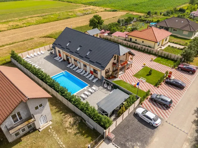 Vedere aeriană largă a pensiunii, cu piscină, parcare și mașini, într-un cartier rezidențial