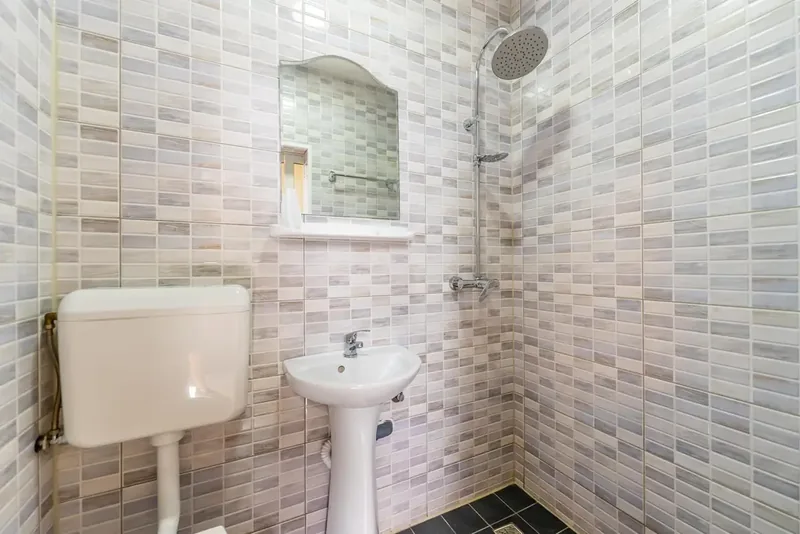 Baie proprie placată cu faianță, cu duș, lavoar și oglindă